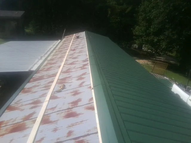 Old rusted panels beside newly installed green metal roofing — Wind Damage Roof Repair by Roofing Brothers in Pittsburg