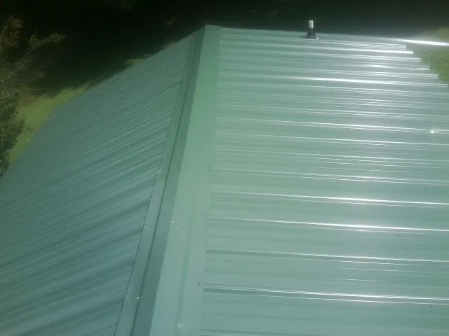 New green metal panels meeting at the ridge of a roof — Flat Roof Repair work by our crew in Pittsburg