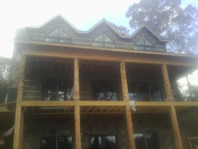 Dormers and porch framing on a large log home under construction — Roof Coating work by our crew in Pittsburg